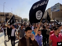 FILE - Young men chant pro-Islamic State slogans as they wave the group's flags in Mosul, Iraq.