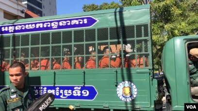 Youth activist Kong Raiya waves his hand as a van carries him along with other prisoners from Prey Sar prison to the Phnom Penh Municipal Court, in Phnom Penh, on Nov. 26, 2019. (Hul Reaksmey/VOA Khmer)