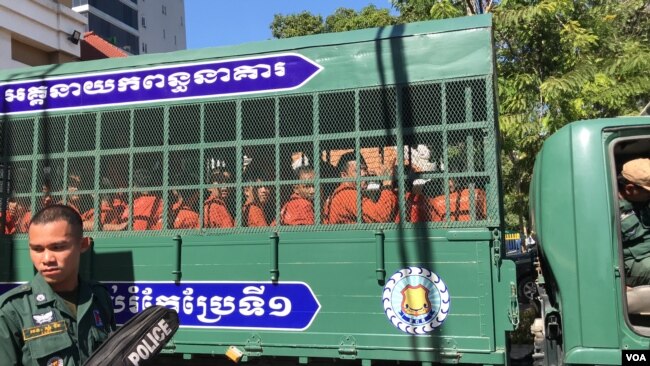 Prisoners wearing orange jumpsuits sit in a van en route from Prey Sar prison to the Phnom Penh Municipal Court, Cambodia, November 26, 2019. (Hul Reaksmey/VOA Khmer)