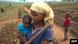 FILE - A woman and her child, who fled from rebel attacks, stand in a field, in Tshikapa, Kasai Region, Democratic Republic of Congo, July 27, 2017.