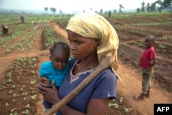FILE - A woman and her child, who fled from rebel attacks, stand in a field, in Tshikapa, Kasai Region, Democratic Republic of Congo, July 27, 2017.