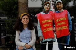 FILE - Esra Ozakca, wife of teacher Semih Ozakca, poses with cut-outs of her husband and fellow dissident, literature professor Nuriye Gulmen, during a protest against their detention, in Ankara, Turkey, June 16, 2017.