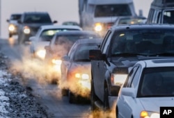 FILE - Car exhaust billows around commuter traffic in winter weather in Omaha, Nebraska, Feb. 1, 2013.