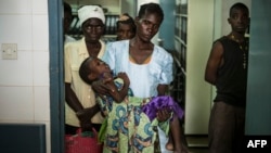 FILE - An HIV-positive mother holds her sick child at the Thyolo District hospital in Malawi, Nov. 26, 2014. 