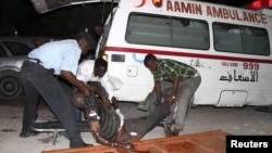 Somali policemen move a victim after a suicide bomb attack at Village restaurant in Mogadishu, September 20, 2012.