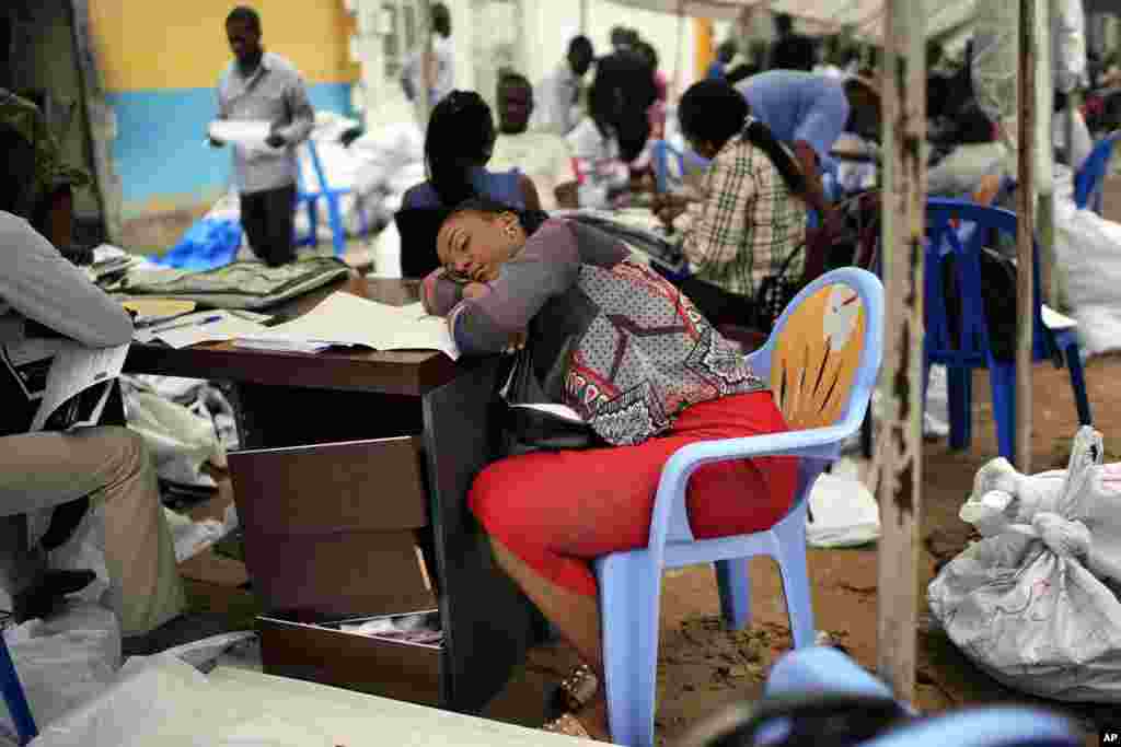 An exhausted Congolese independent electoral commission (CENI) official rests as results are tallied for the presidential election, at a local results compilation center in Kinshasa, Democratic Republic of Congo.