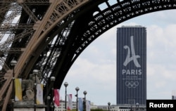 FILE - The logo of the Paris candidacy for the 2024 Olympic and Paralympic Games is seen on the Montparnasse tower behind the Eiffel Tower in Paris, July 11, 2017.