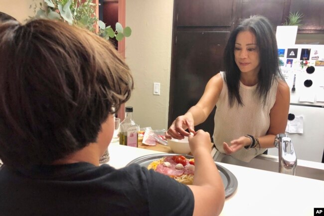 Keryn Francisco membuat pizza bersama putranya Reve Francisco (10 tahun) di Alameda, California, Selasa, 2 November 2021. (AP Photo/Haven Daley)