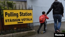 Čovek i dečak prolaze pored natpisa za policijsku stanicu pre referenduma o abortusu zakazanog za 25. maj, u Dablinu, Irska, 22. maja 2018.