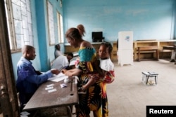 A woman carries her baby after voting at a polling station during the presidential election in Kinshasa, Democratic Republic of Congo, Dec. 30, 2018.