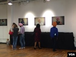 Sikh Coalition volunteers speak with visitors as they look at portraits from the Sikh Project. (E. Sarai/VOA)