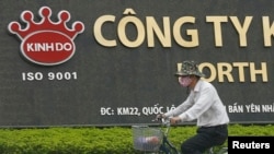 FILE - A man rides a bicycle past a Kinh Do factory in Vietnam's northern Hung Yen province, outside Hanoi.