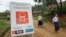 ນັກ​ຮຽນ​ຍ່າງ​ຜ່ານ​ປ້າຍ​ເຕືອນ​ເຂດ​ທີ່​ກຳ​ລັງ​ຢູ່​ພາຍ​ໃຕ້​ການ​ເກັບ​ກູ້​ລະ​ເບີດ ໂດຍ​ກຸ່ມ​ເກັບ​ກູ້​ລະ​ເບີດ UXO. ແຂວງ​ຊຽງ​ຂວາງ. 3 ເມ​ສາ 2008.