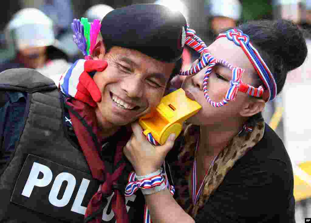 An anti-government protester blows a giant whistle to a riot police officer outside the headquarters of Prime Minister Yingluck Shinawatra&#39;s ruling Pheu Thai Party in Bangkok, Thailand.