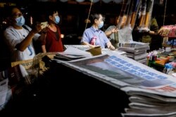 People discuss the fate of the Apple Daily newspaper at a newspaper stall following police raids and the arrest of executives in Hong Kong on June 22, 2021. Reuters/Tyrone Siu