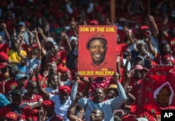 Supporters of the Economic Freedom Fighters (EFF) party hold up an election poster of leader Julius Malema during a May Day Rally in Alexandra Township, Johannesburg, May 1, 2019.