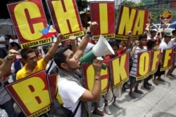 FILE - Filipinos chant anti-China slogans over the disputed Scarborough Shoal islands in the South China Sea claimed by both nations as they march toward the Chinese consulate in the Makati financial district of Manila, Philippines, May 11, 2012.