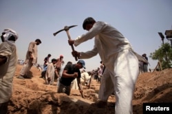 FILE - Members of the Ahmadi Muslim community dig graves for victims in Chenab Nagar, located in Punjab's Chiniot District, about 200 km (124 miles) northwest of Lahore. At least 70 people were killed in the attack.