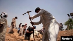 FILE - Members of the Ahmadi Muslim community dig graves for victims in Chenab Nagar, located in Punjab's Chiniot District, about 200 km (124 miles) northwest of Lahore. At least 70 people were killed in the attack.