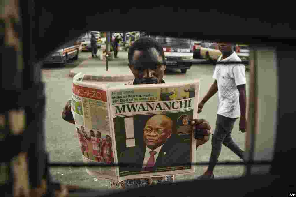 A man reads a newspaper with a headline announcing the death of Tanzania&#39;s President John Magufuli in Dar es Salaam.