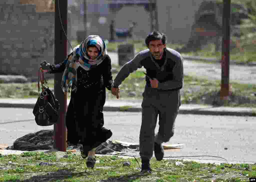 Iraqis run for cover as they flee Mosul&#39;s Al-Tayaran neighborhood during an offensive by Iraqi forces to retake the area from Islamic State (IS) group fighters.