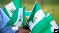 An unidentified woman sells Nigerian national flags, during an event to mark Nigeria independence day, in Lagos, Nigeria. Tuesday, Oct. 1, 2013 . Nigeria marked 53 years of independence Tuesday with little to celebrate, scores of families are in mourning