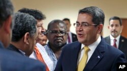 FILE - Honduran President Juan Orlando Hernandez, right, greets Honduran community leaders and guests in Doral, Fla., June 14, 2017. Honduran community leaders and families raised concerns about their fates after their Temporary Protected Status expires Jan. 5, 2018.