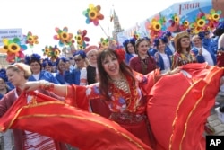 Russians dance as they parade on Red Square to mark May Day in Moscow, May 1, 2017, with the Spassky Kremlin tower in the background.