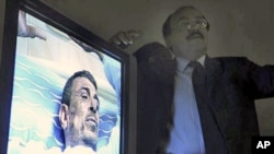 A monitor displays video of 48-year old Abdou Abdel-Monaam Hamadah, at a Cairo hospital, as unidentified plastic surgeon, right, talks about the medical case. Hamadah apparently set himself on fire Monday outside the country's parliament in a personal pr