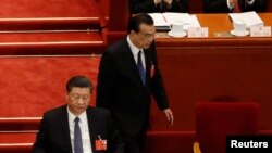 中国总理李克强在北京人大会堂举行的全国人大年度会议开幕式上发表讲话后返回习近平旁的座位。（2020年5月22日）