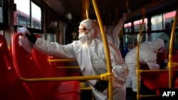 Des employées colombiennes désinfectant un bus à la gare routière de Bogota, afin de prévenir la propagation du nouveau coronavirus, 15 mars 2020. (Photo AFP/Raul Arboleda)
