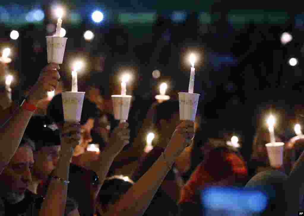 Attendees raise their candles at a candlelight vigil for the victims of the shooting at Marjory Stoneman Douglas High School, in Parkland, Fla., Feb. 15, 2018. 