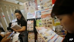 FILE - In this June 24, 2016 photo, visitors read leaflets on hotels in Japan at the Japan Tourism Fair in Bangkok, Thailand.