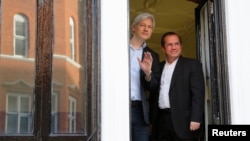 WikiLeaks founder Julian Assange waves from a window with Ecuador's Foreign Affairs Minister Ricardo Patino (R) at Ecuador's embassy in central London June 16, 2013. 
