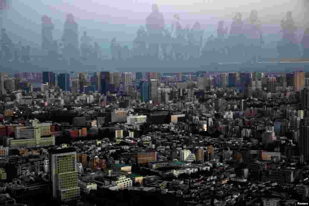 People are reflected as they observe on the Shibuya Sky observation deck in Tokyo, Japan.