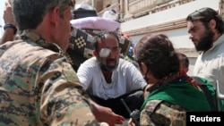 Syria Democratic Forces fighters chat with an injured civilian who was evacuated with others by the SDF from an Islamic State-controlled neighborhood of Manbij, in Aleppo Governorate, Syria, Aug. 12, 2016. The SDF has said Islamic State was using civilian
