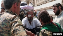 Pejuang Pasukan Demokrasi Suriah (SDF) berbicara dengan warga sipil yang terluka di Manbij, Suriah utara (12/8). 
