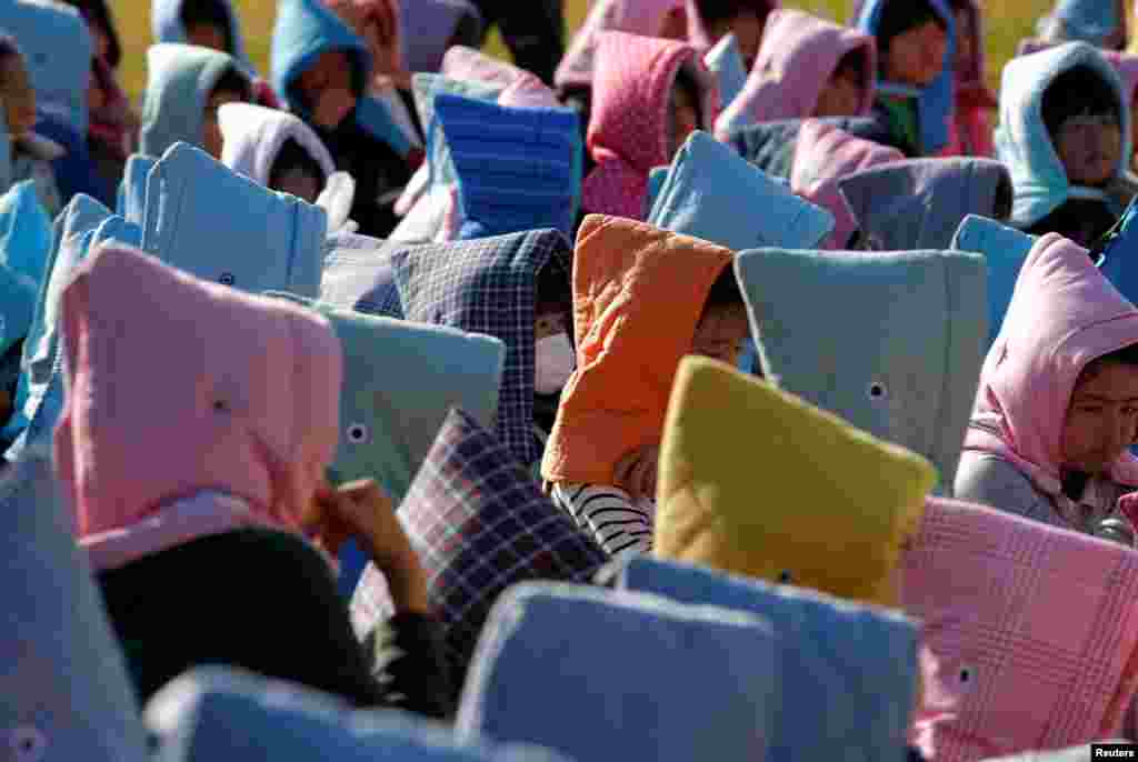 Schoolchildren wearing padded hoods to protect them from falling debris gather in an evacuation shelter on a hill during a tsunami simulation drill ahead of World Tsunami Awareness Day at Futaba elementary school in Choshi, Chiba Prefecture, Japan.