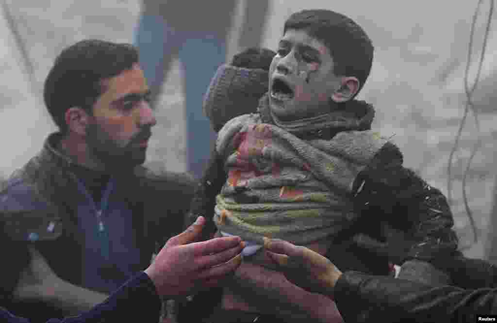 Men help a wounded boy who survived what activists say was an airstrike by forces loyal to Syrian President Bashar al-Assad in the Duma neighborhood of Damascus, Jan. 7, 2014. 
