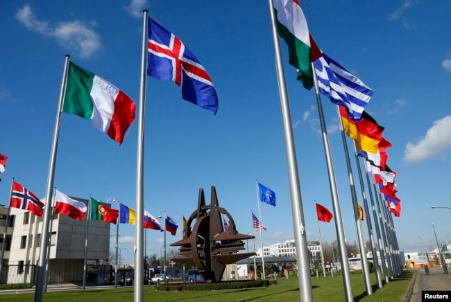 FILE - Flags fly at NATO headquarters in Brussels, Belgium, March 2, 2014. President Donald Trump has repeatedly asserted that member nations need to pay their fair share in defense spending.