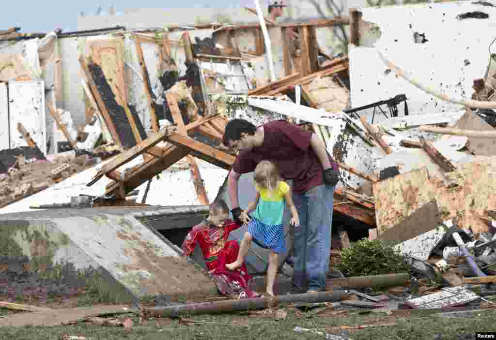 Un hombre y sus dos ni&ntilde;os abandonan su vivienda que qued&oacute; destruida tras el paso del tornado.
