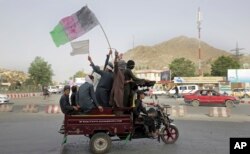 FILE - Taliban fighters and their supporters carry a representation of the Afghan national flag and a Taliban flag while riding in a motorized vehicle, in Kabul, Afghanistan, June 17, 2018.
