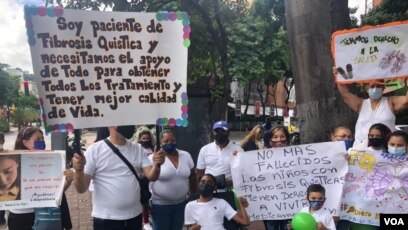 Pacientes con fibrosis quística y sus familiares sostienen su pancartas durante una protesta en Caracas, en octubre de 2021.