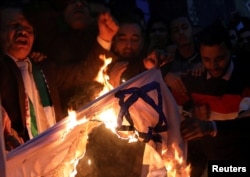 People shout slogans against Israel while burning a makeshift Israeli flag during a protest against U.S. President Donald Trump's Jerusalem declaration, in front of the Syndicate of Journalists in Cairo, Egypt, Dec. 7, 2017.