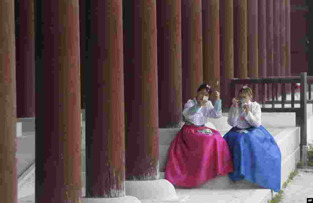 Women in South Korean traditional "Hanbok" attire fix their make up at the Gyeongbok Palace, during the Joseon Dynasty in Seoul.