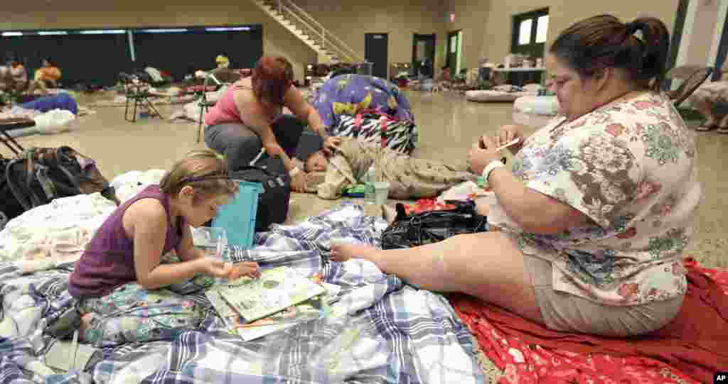 Krystal Ledet, back left, looks after her son, Brandon Malbrough as her daughter Alexus Malbrough, left, colors with her grandmother, Melissa Rodrigue, right, after evacuating to a shelter in Houma, La., Aug. 28, 2012. 