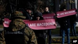 A group of people hold banners reading "We are Macedonia" during an anti-NATO protest in front of the Parliament in Skopje, Macedonia, while NATO Secretary General Jens Stoltenberg addresses the lawmakers in the Parliament building, Jan. 19, 2018.