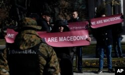 FILE - A group of people hold banners reading "We are Macedonia" during an anti-NATO protest in front of the Parliament in Skopje, Macedonia, while NATO Secretary General Jens Stoltenberg addresses the lawmakers in the Parliament building, Jan. 19, 2018.