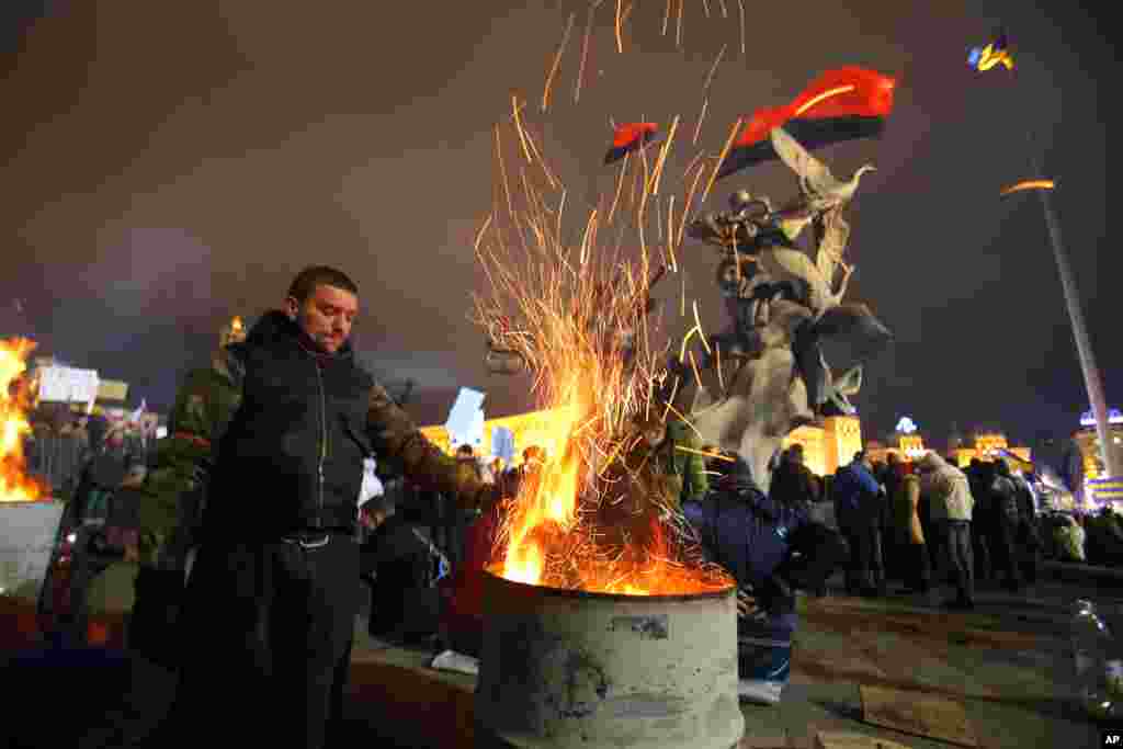 People warm themselves by a fire in a steel drum during a rally in support of Ukraine's integration with the European Union in Kyiv, Nov. 28, 2013.