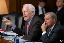 Sen. John Cornyn, R-Texas, left, chairman of the Subcommittee on Immigration, Refugees and Border Security, joined at right by Sen. Lindsey Graham, R-S.C., chairman of the Subcommittee on Crime and Terrorism, questions witnesses as the Senate Judiciary Committee holds a hearing on the Trump administration's policies on immigration enforcement and family reunification efforts, on Capitol Hill in Washington, July 31, 2018.